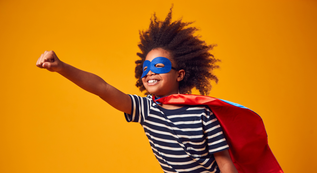 boy with a big smile dressed as superhero against orange background