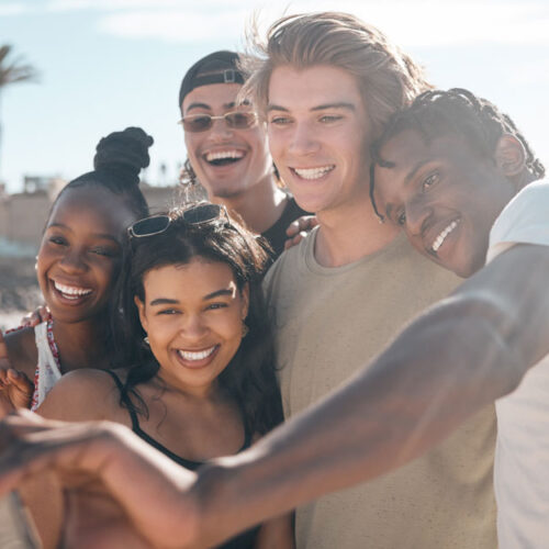 Group Of Young Adults Stand Together For A Selfie On The Beach