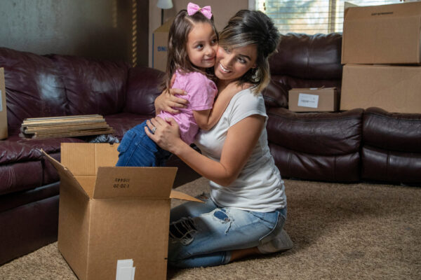 A Happy Hispanic Mother And Child Packing Boxes