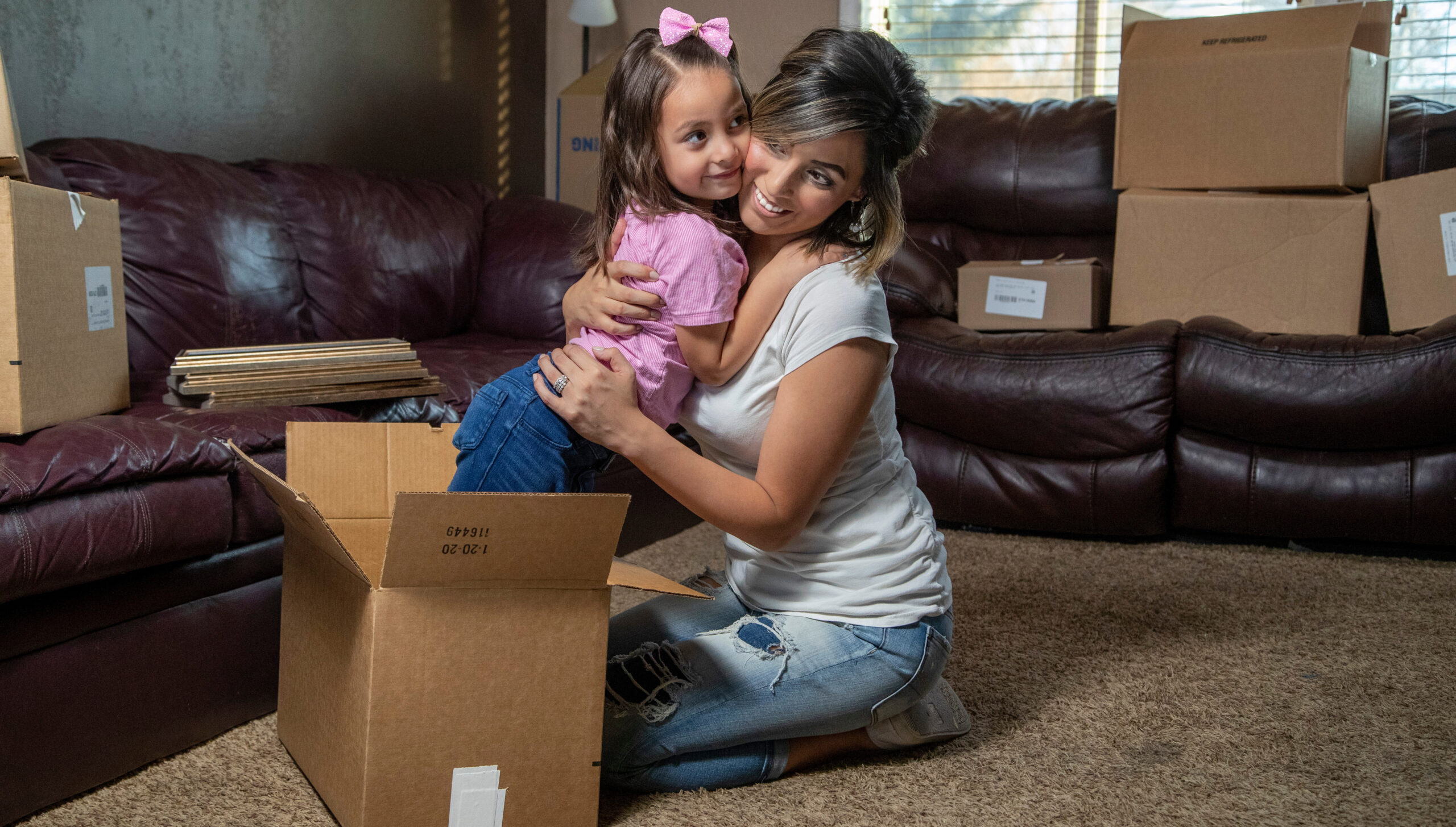 A happy Hispanic mother and child packing boxes