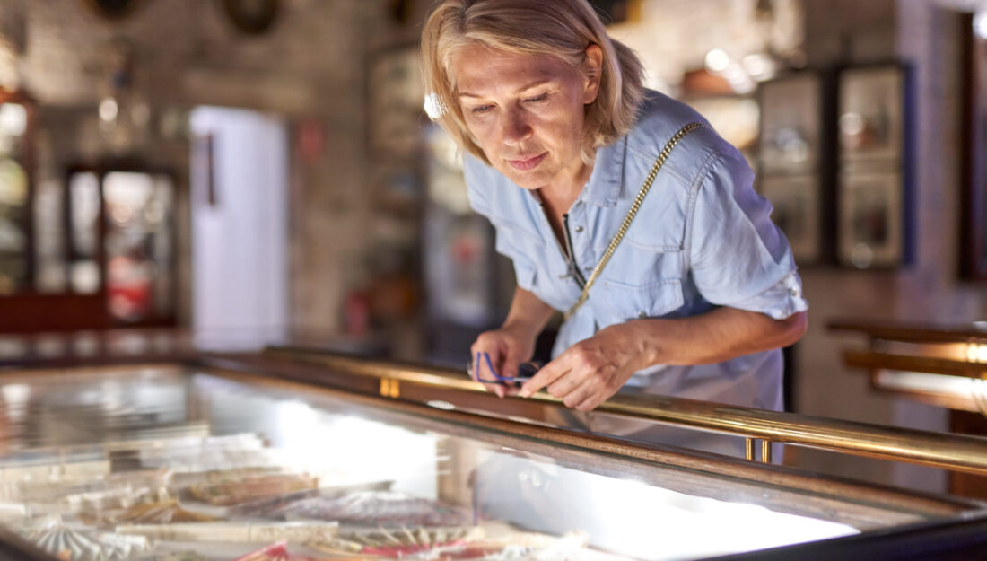 Woman visitor in a historical museum looking at art object in a case.